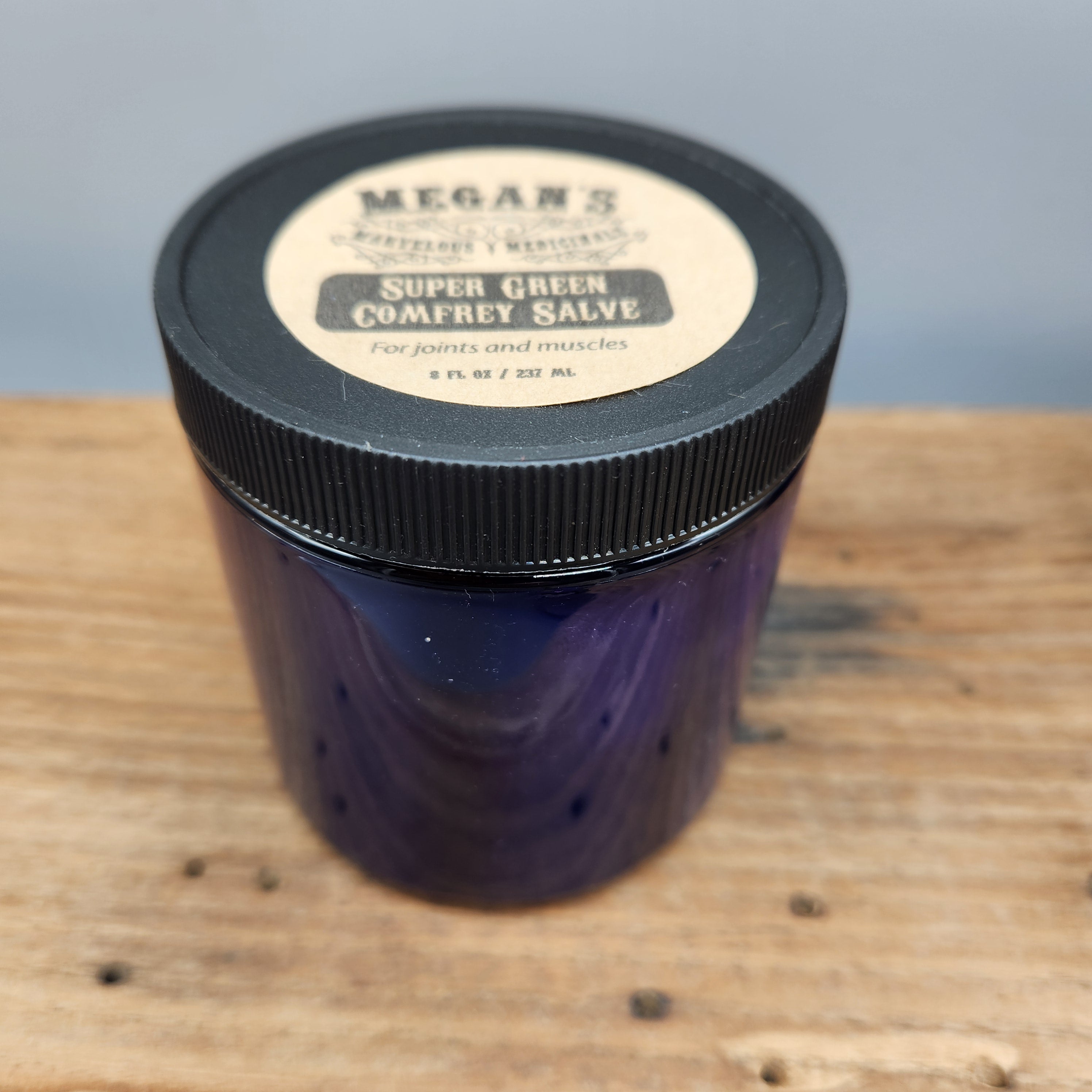 Jar of Megan's Marvelous Medicinals super green comfrey salve 8oz jar on a wooden surface